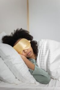 person resting on a pillow wearing a gold sleep mask